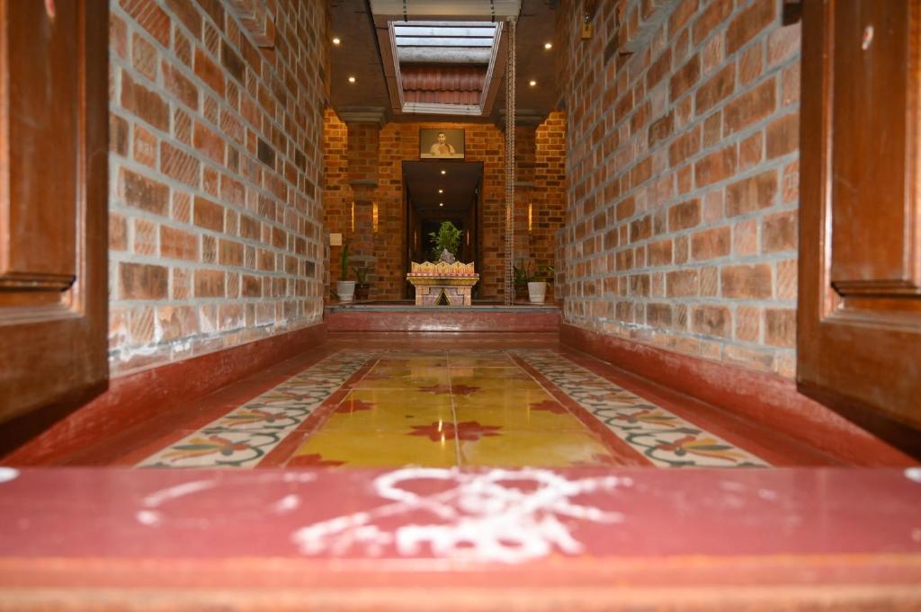 a hallway with a tile floor and a brick wall at Mutram Heritage Stay in Kanchipuram