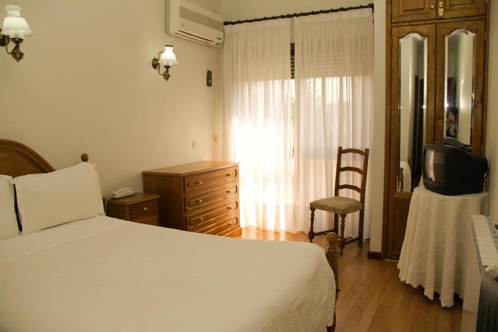 a bedroom with a bed and a chair and a television at São Neutel in Chaves