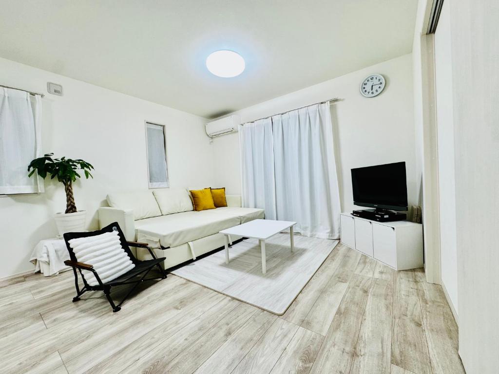 a white living room with a couch and a tv at Villa 勝浦 in Katsuura