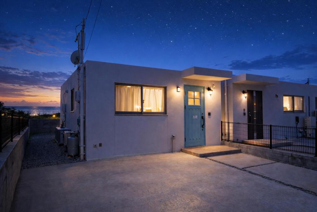a white house with a blue door at night at Klasse Villa Miyako in Miyako-jima