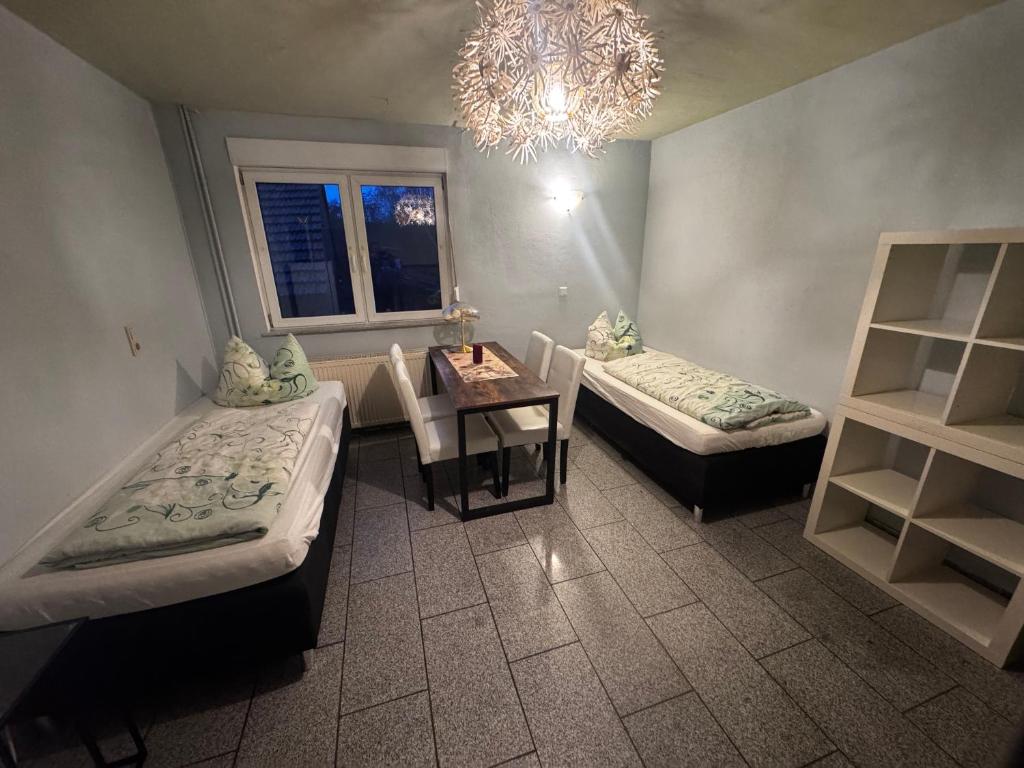 a room with two beds and a table and a chandelier at Bauernhof Privatzimmer Free WiFi Gemeinschaftsbad in Hausbreitenbach