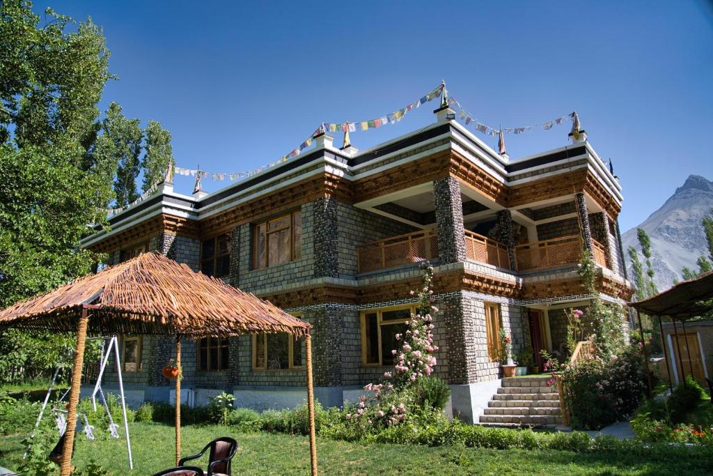 a large brick house with a straw umbrella in front of it at Semba retreat in Hundar