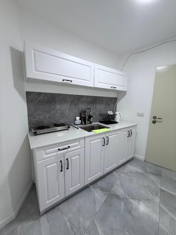 a white kitchen with a sink and a refrigerator at Urban garden loft 3 in Haifa