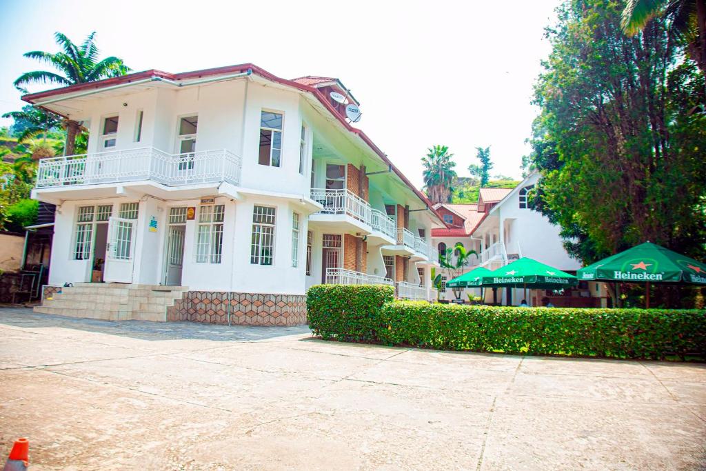 a white house with green umbrellas in front of it at Musanto Hotel in Gisenyi