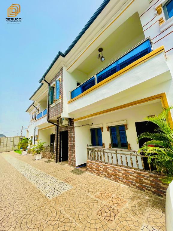 a white house with blue windows and a driveway at Derucci Luxury Apartment in Owerri