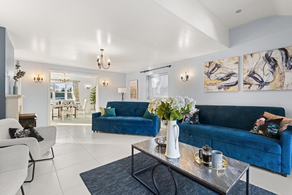 a living room with blue couches and a table at Northbrook in Tackley