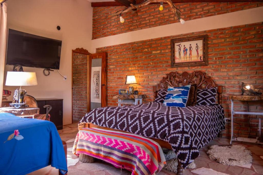 a bedroom with a bed and a brick wall at Cabaña Renacer in Samaipata