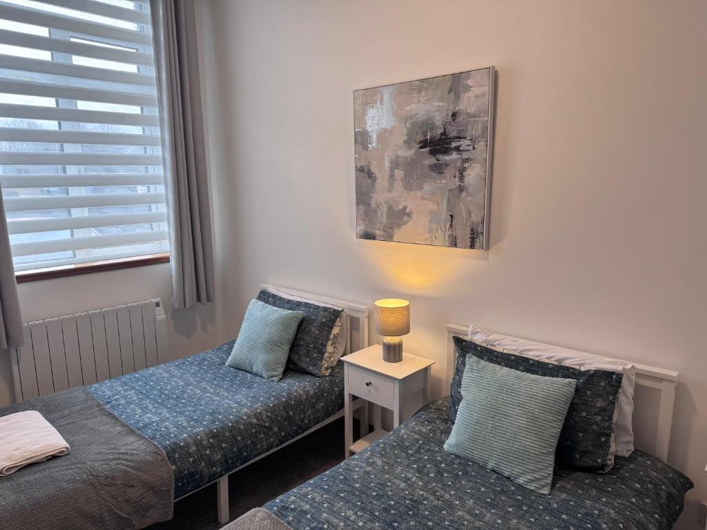 a bedroom with two beds and a lamp on a table at Ben Lomond Apartment - Macaulay Letting in Alexandria