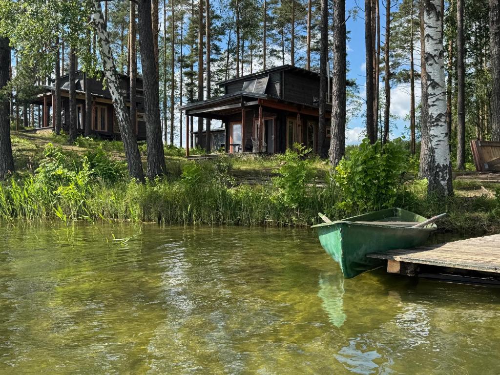 a boat sitting on the water in front of a cabin at Jazinks Sunset 4 in Apšenieki