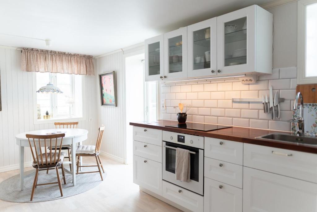 a kitchen with white cabinets and a table and chairs at Toftenäs apartment in Toftenäs
