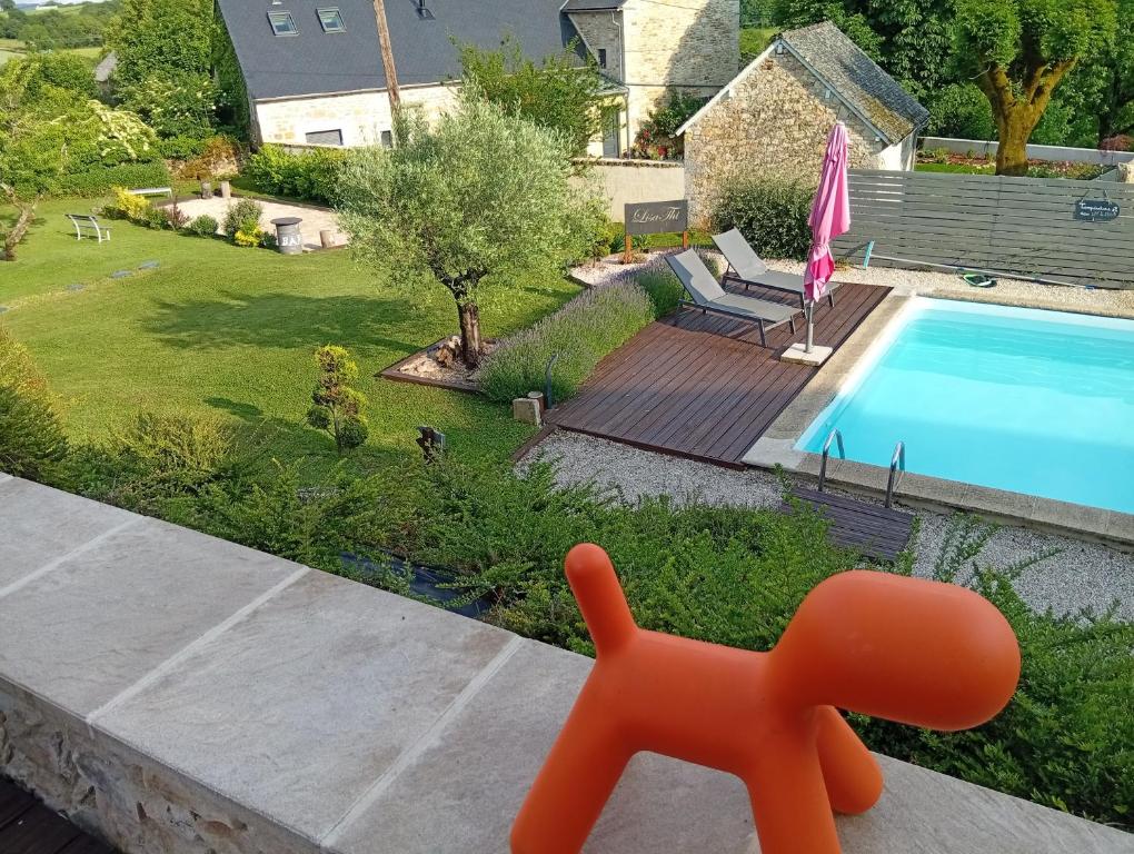 an orange toy dog sitting on a porch next to a swimming pool at Lili de La LisaThi in Cruéjouls