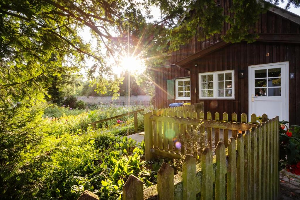 a wooden house with a fence and a garden at Pförtnerhaus in Gartow