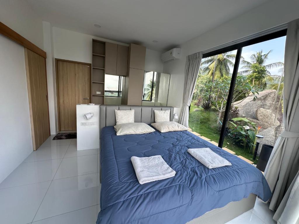 a bedroom with a blue bed and a large window at ON THE RoCK SEAVIEW in Ban Nua