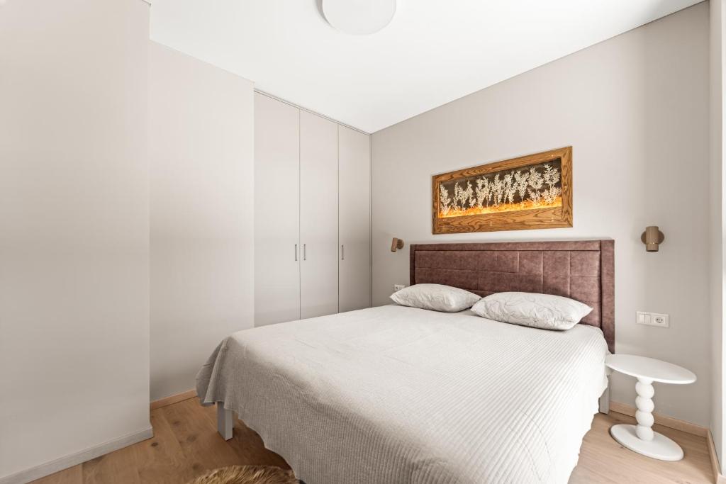 a bedroom with a bed and a painting on the wall at Dunique Summer in Palanga