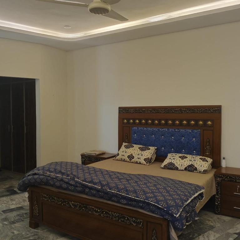 a bedroom with a bed with a blue comforter and pillows at Wali Rest House 1 in Rahimyar Khan