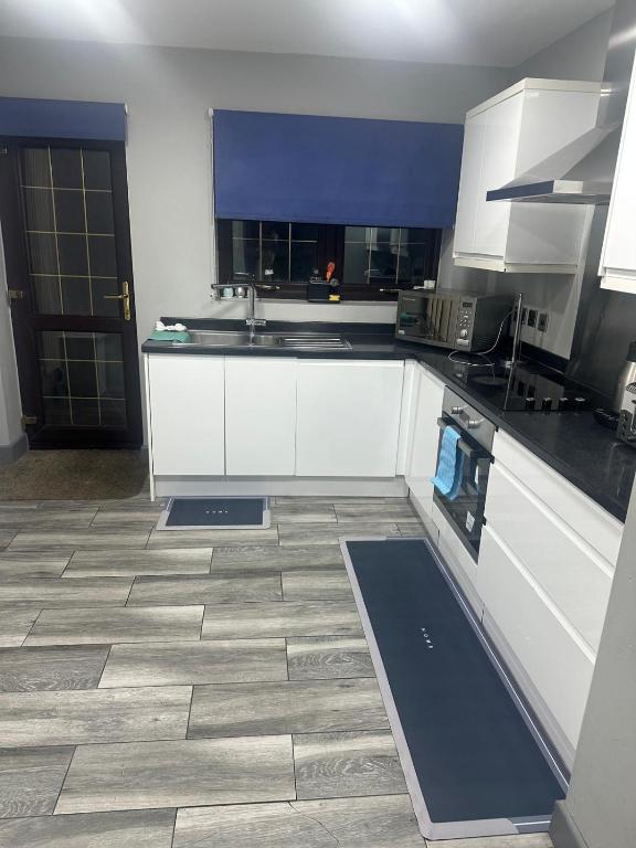 a kitchen with white cabinets and a tile floor at Marvel Abbeywood, Luxury 3 bedroom House with parking, 2mins walk to Elizabeth Line in Abbey Wood