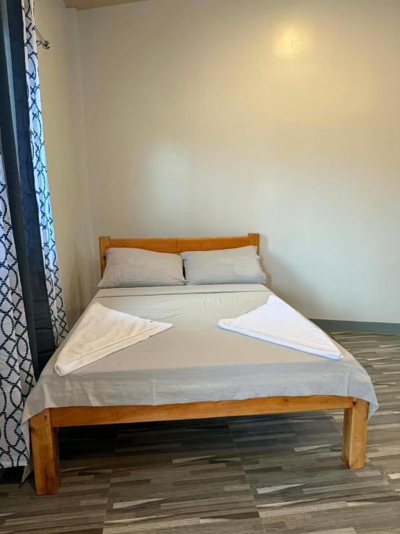 a bed with white sheets and a wooden frame in a room at New Apartment in Panglao Island