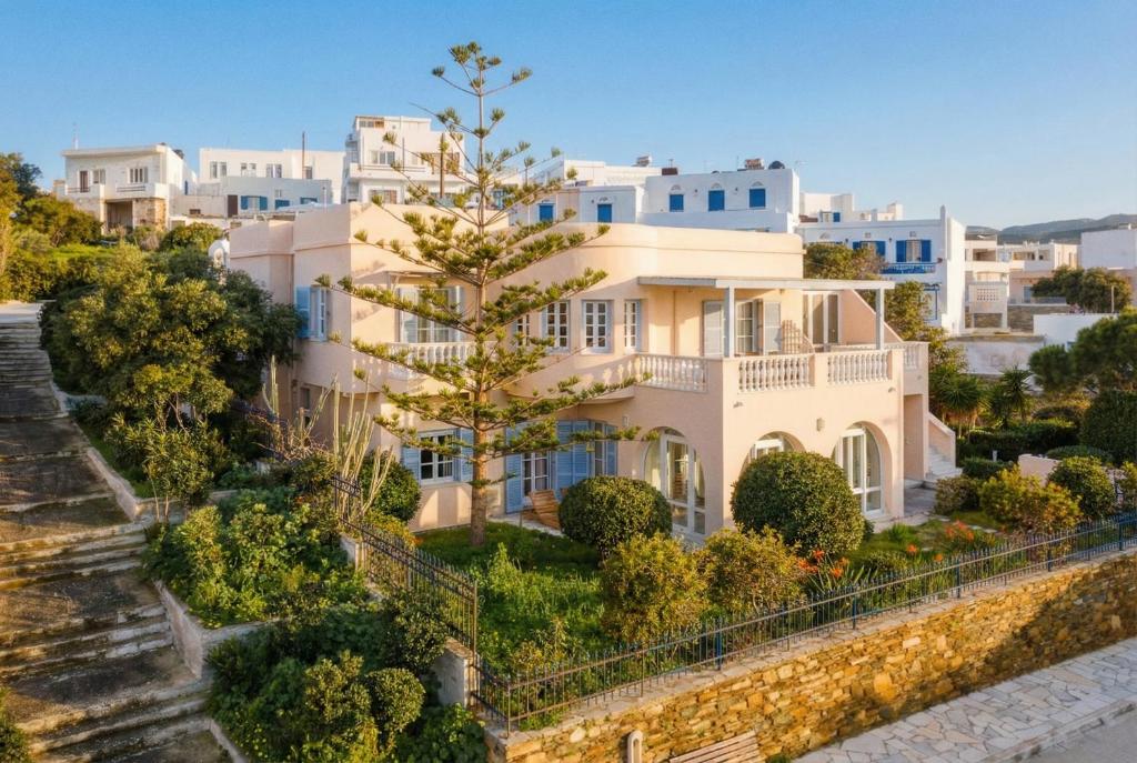 a large white house with a tree in front of it at Seashore Villas Tinos in Tinos