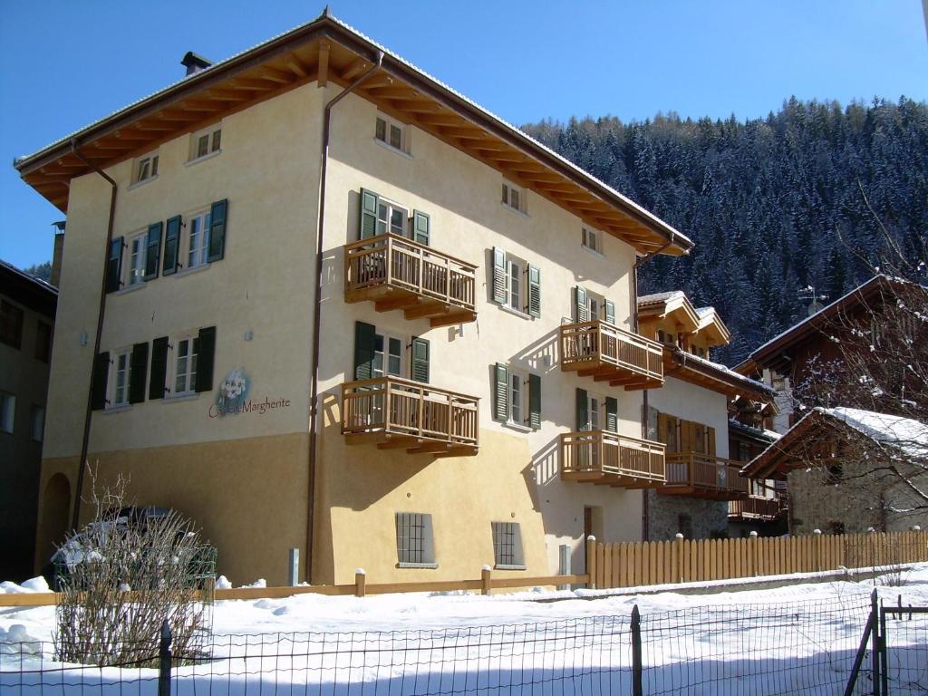 een gebouw met balkons en een hek in de sneeuw bij Residence Ca' Delle Margherite in Pellizzano