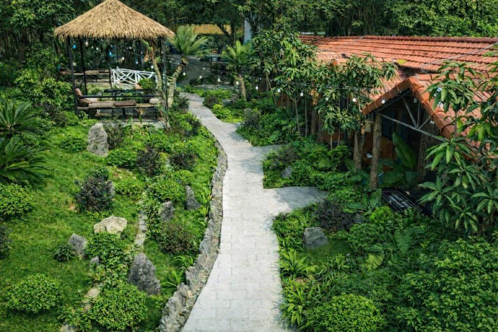 a garden with a stone pathway and a building at Trang An river mountain ecolodge Ninh Binh in Ninh Binh