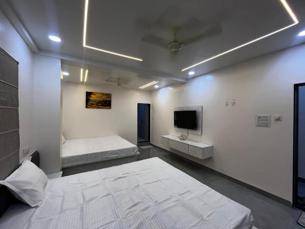 a room with two beds and a flat screen tv at Hotel Tulsi in Aurangabad