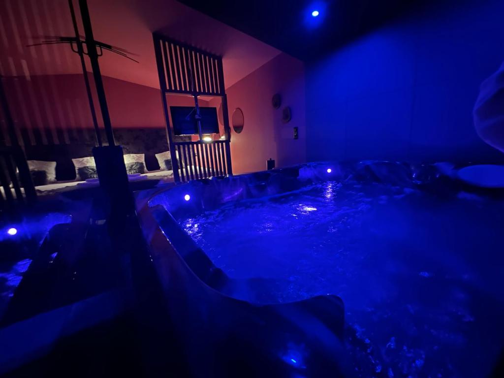a dark room with a hot tub with blue lights at Love room Jacuzzi - Litchi in Bordeaux