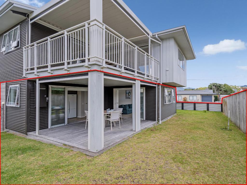 a house with a deck with a table on a lawn at Soleil Studio - Whangamata Self-contained Unit in Whangamata