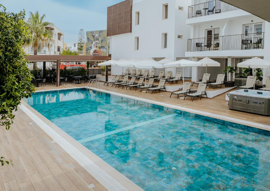 a swimming pool with chairs and a building at Cosmo Napa Boutique Hotel in Ayia Napa