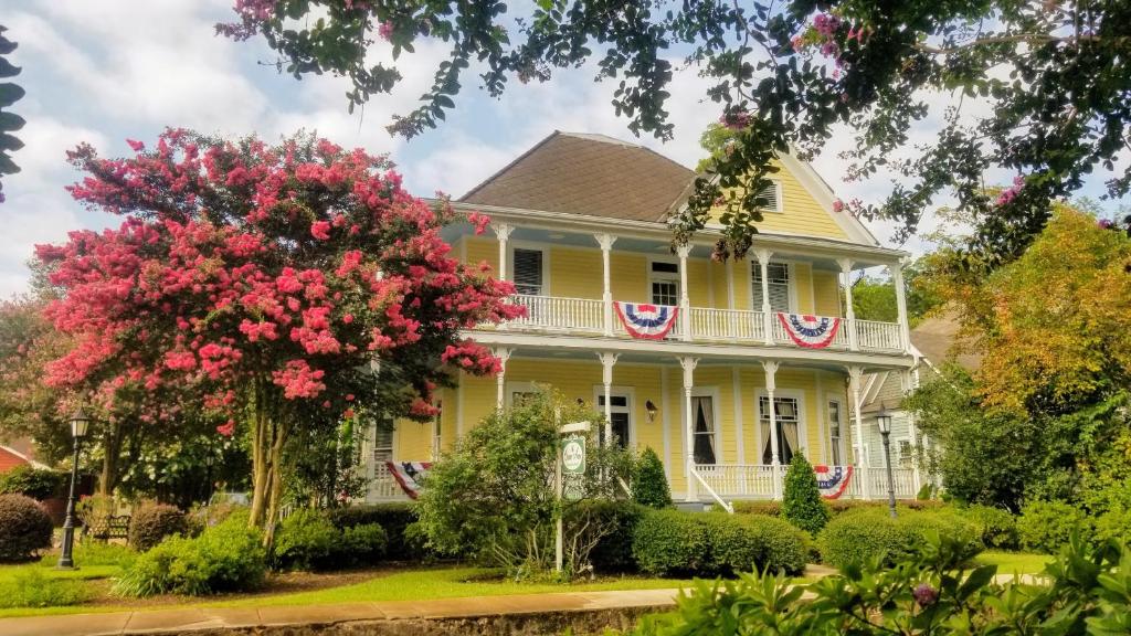 a yellow house with american flags on it at The Queen Anne Bed & Breakfast in Natchitoches