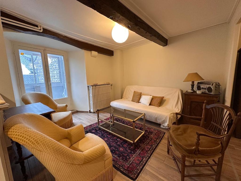 a living room with a bed and a table and chairs at Murat - La maison de la petite place in Murat