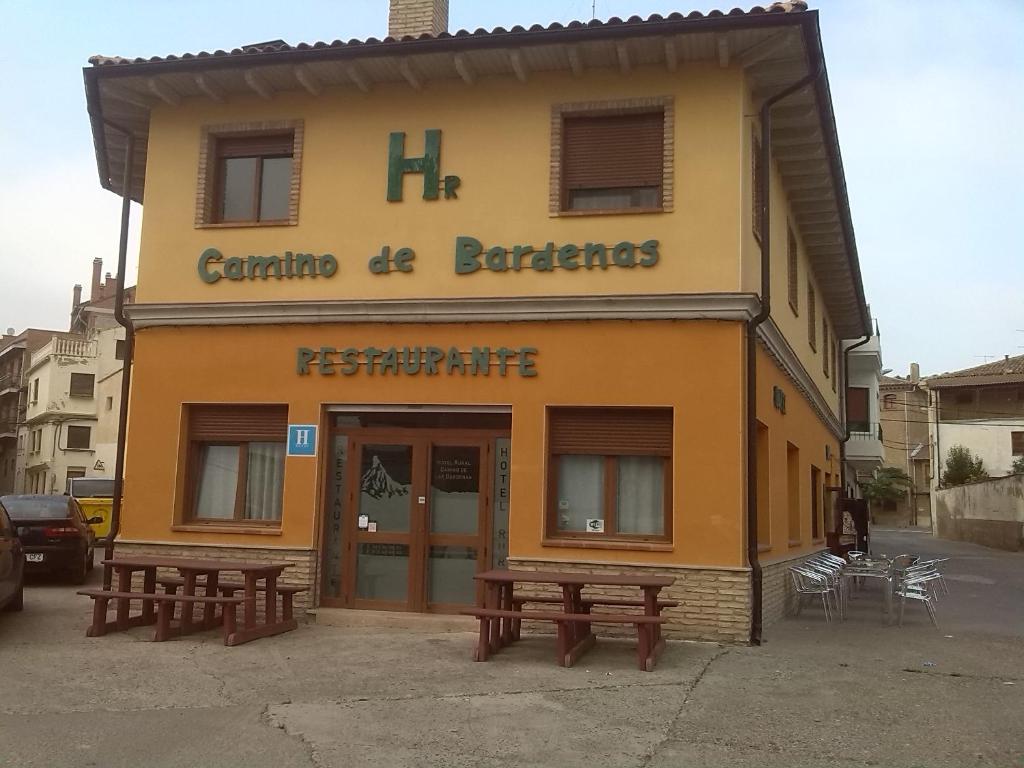 un bâtiment avec deux bancs devant lui dans l'établissement Camino de las Bardenas, à Arguedas