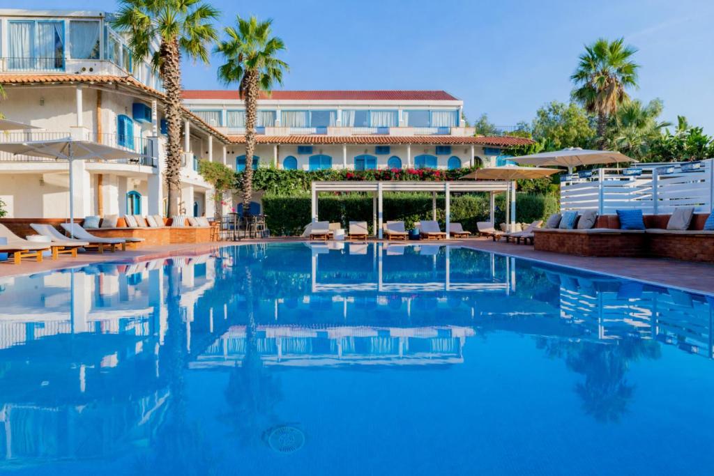 a swimming pool in front of a building with palm trees at Le Dune Sicily Hotel in Catania