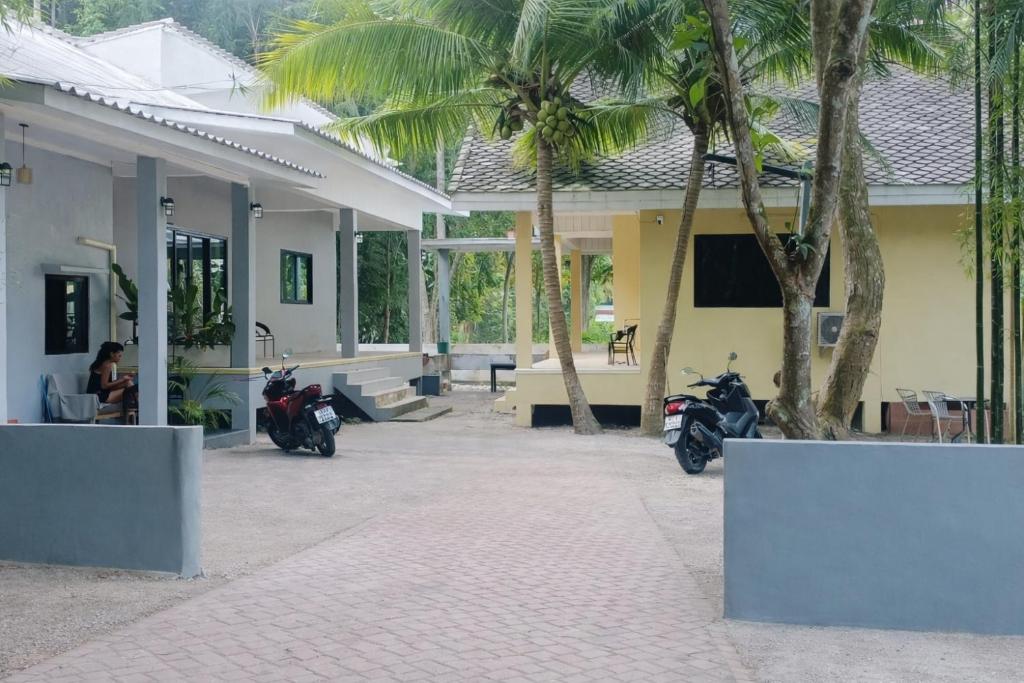 two motorcycles parked outside of a building with palm trees at Jeab Villa Kohphangan in Ko Phangan