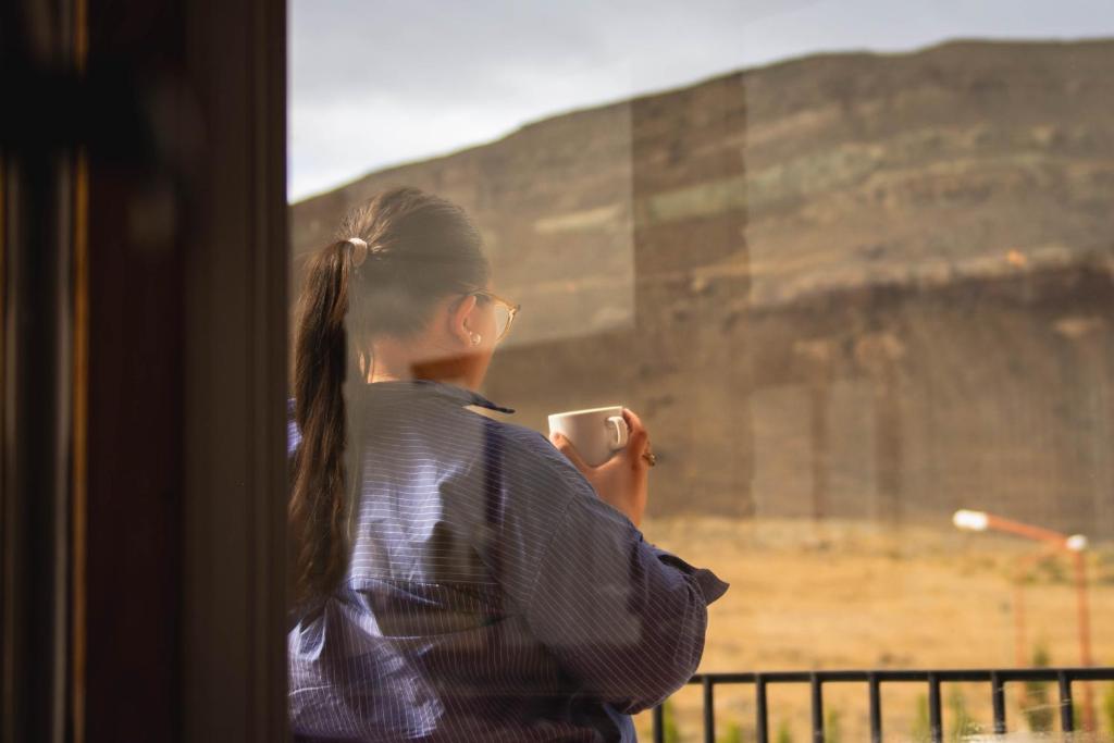 a woman taking a picture of the coliseum through a window at Hosteria Casa kuyen in El Calafate