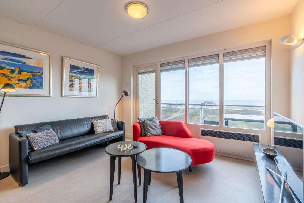 a living room with a couch and a red chair at Appartementencomplex Juliana 152 in De Koog