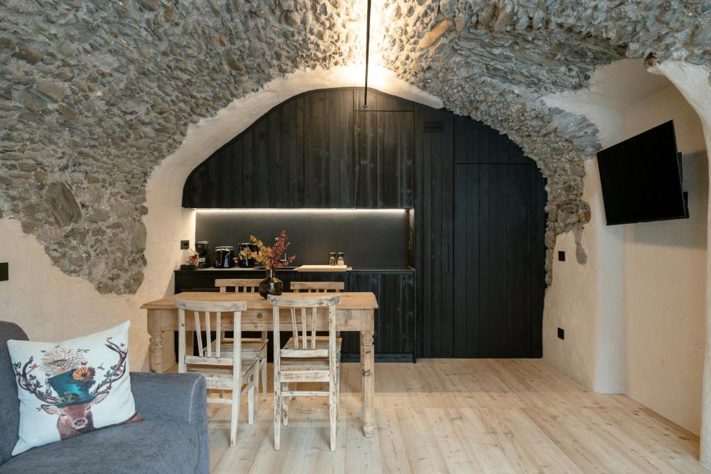 a dining room with a table and a black door at Grotta Bàlzer in Valdidentro