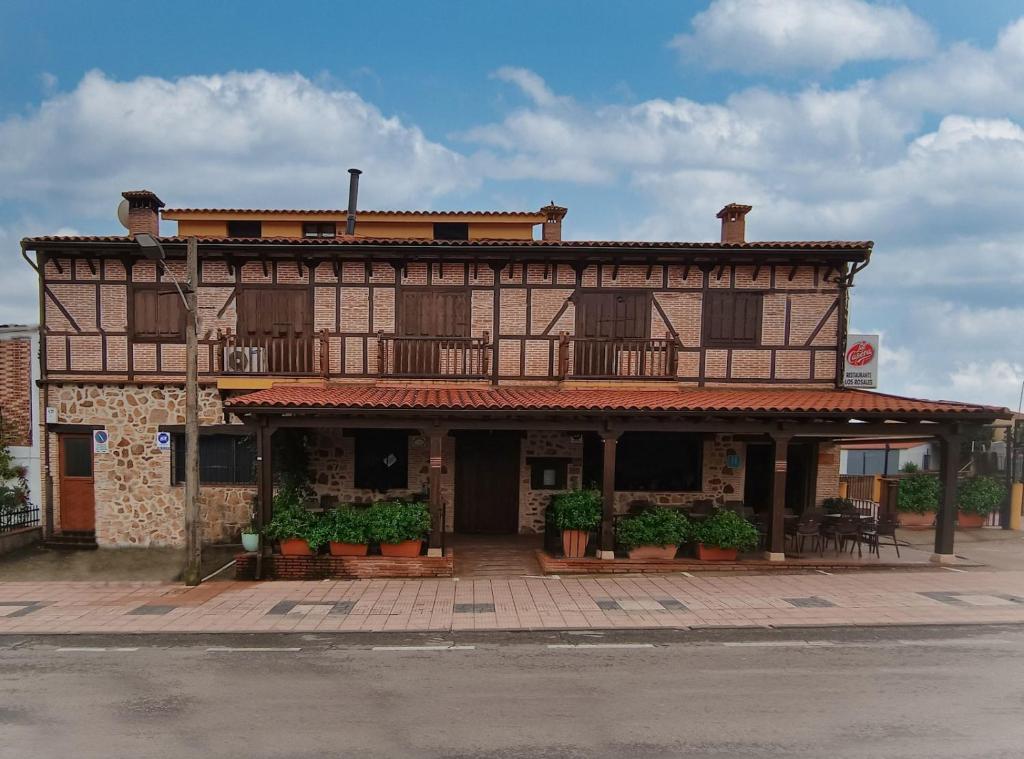 an old building with potted plants in front of it at Hostal Los Rosales in Tejeda de Tiétar