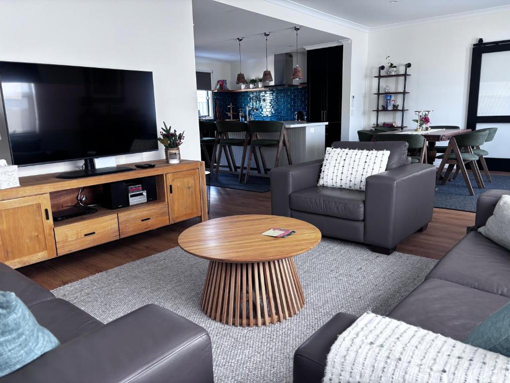 a living room with a couch and a tv and a table at Queensly Cottage in Portland