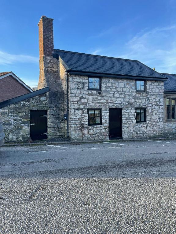 a stone building with two garage doors on a street at Ty capel cottage in Mold