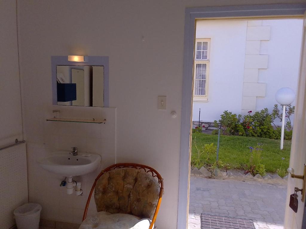a bathroom with a sink and a mirror and a chair at Hotel Prinzessin Rupprecht in Swakopmund