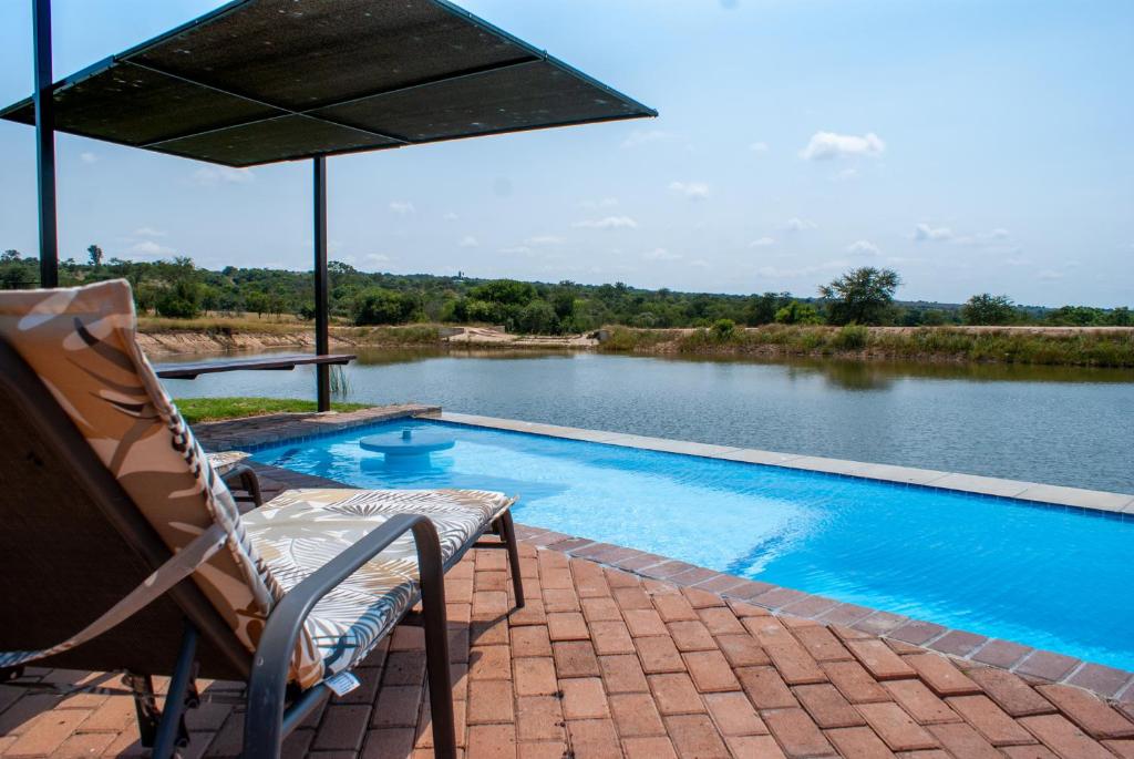 a swimming pool with a chair and an umbrella at Casa de la Presa 4 in Polokwane