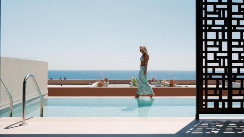 a woman in a dress is standing in a swimming pool at Este Elegant Suites & Villas - Adults Only in Kiotari