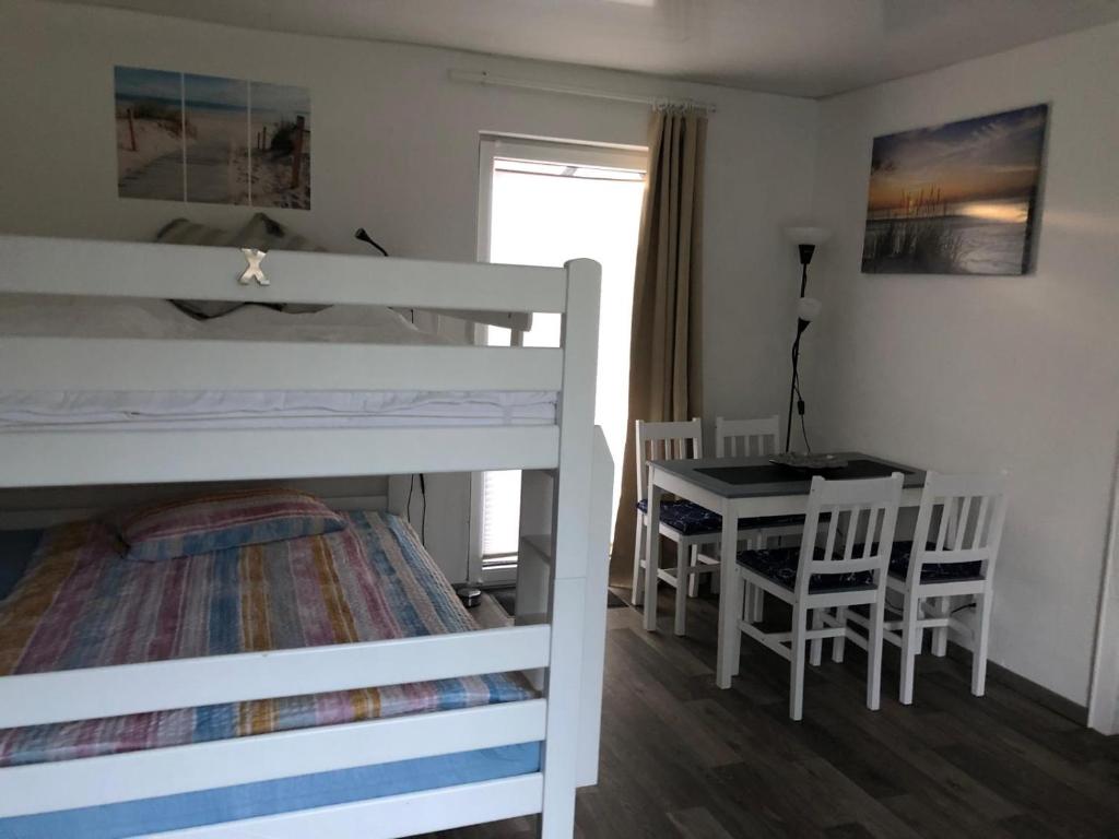 a bedroom with a bunk bed and a table and chairs at FEWO Priel Watt Nr.2 in Cuxhaven