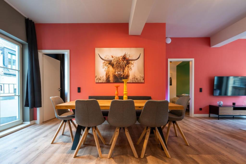 a dining room with red walls and a wooden table and chairs at Marios Mansion in Leipzig