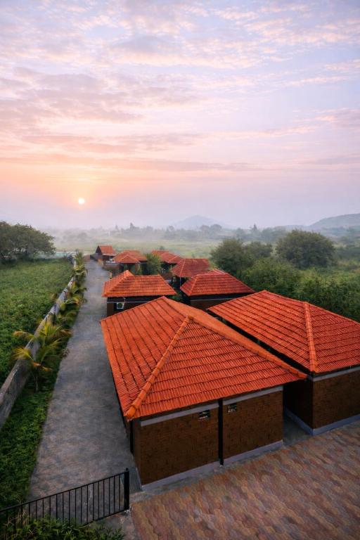 a row of buildings with orange roofs with the sunset in the background at Shwetik Resort in Khamshet