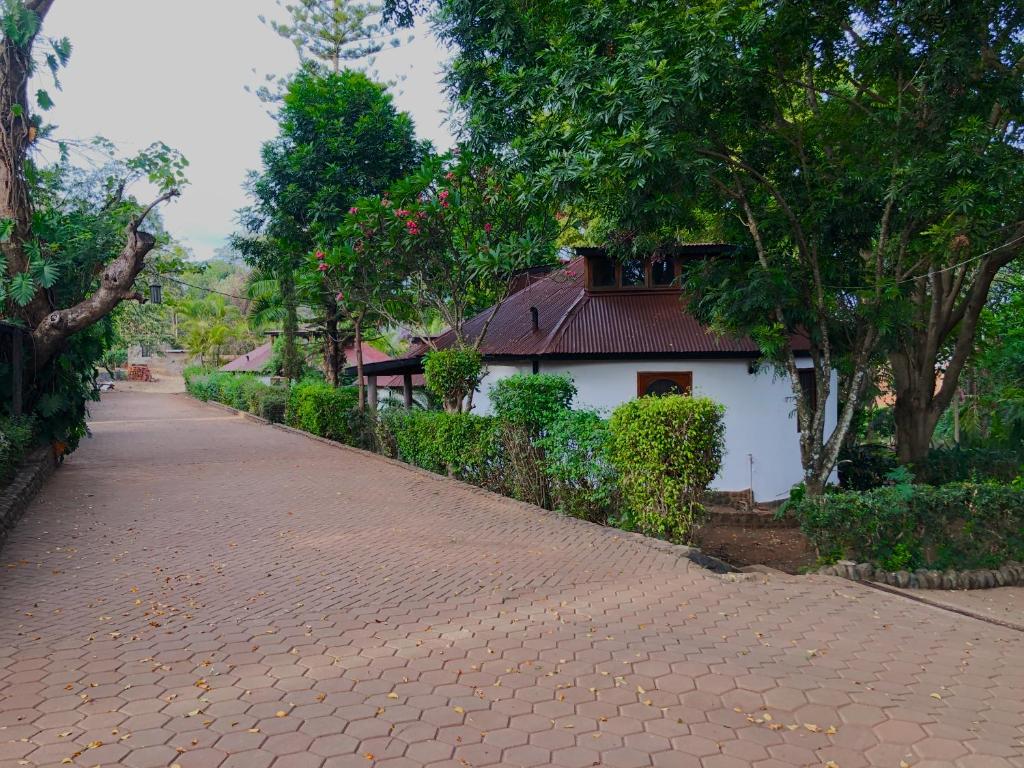 a brick road in front of a white building at Siesta Riverside Cottages Moshi in Shiri