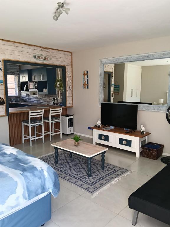 a living room with a bed and a tv and a table at 6 Bayview Seaside Apartment in East London