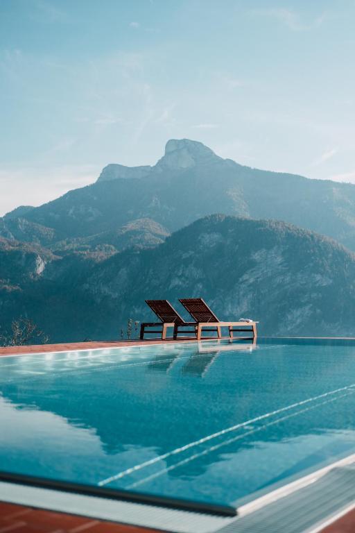 a swimming pool with chairs in front of a mountain at Mondseeblick Apartment KG in Innerschwand