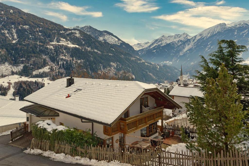 a house covered in snow with mountains in the background at Ferienwohnung Wassermann in Wenns