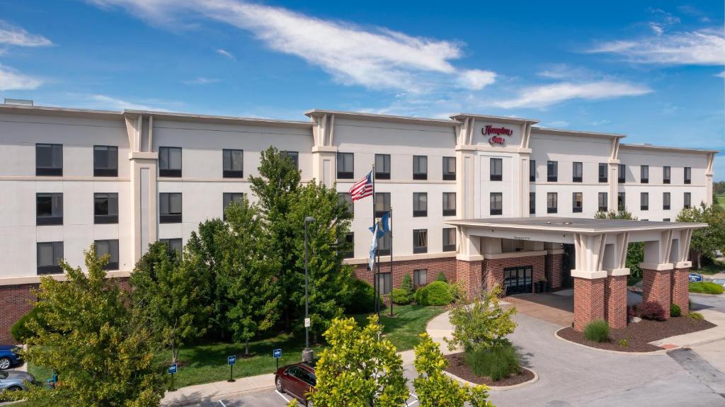 a white building with a flag in front of it at Newly Renovated Hampton Inn Omaha West Lakeside in Lane